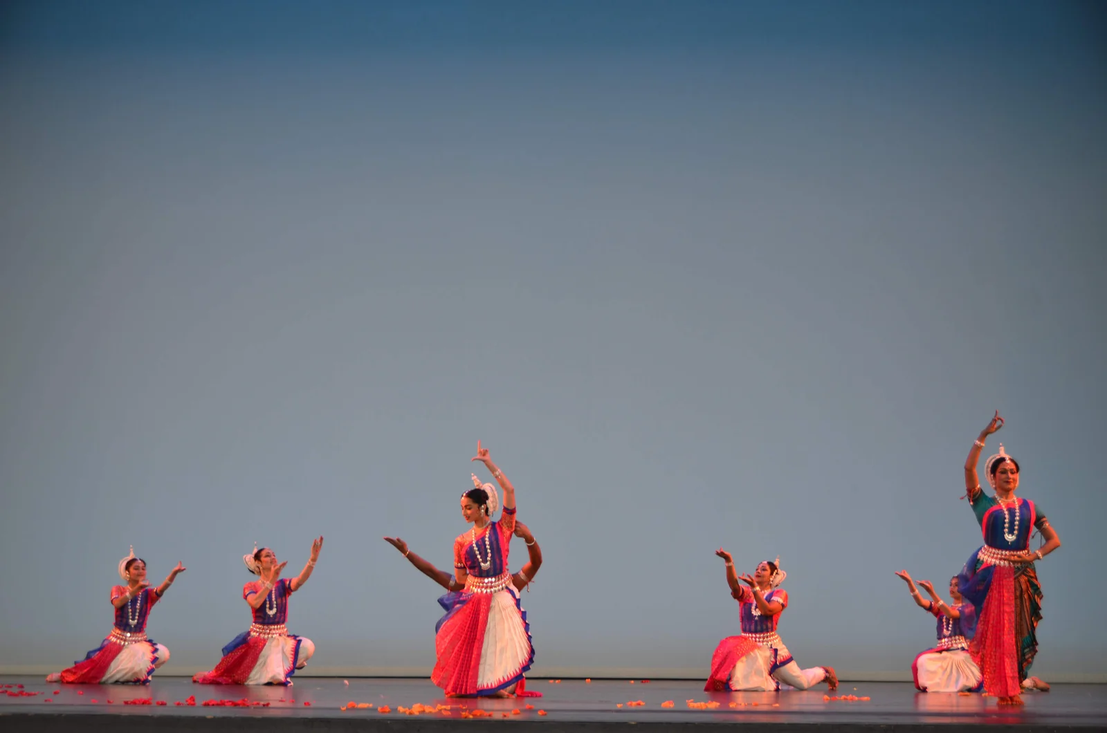 Odissi dancers in traditional attire and jewelry, gracefully poised with hands in expressive gestures