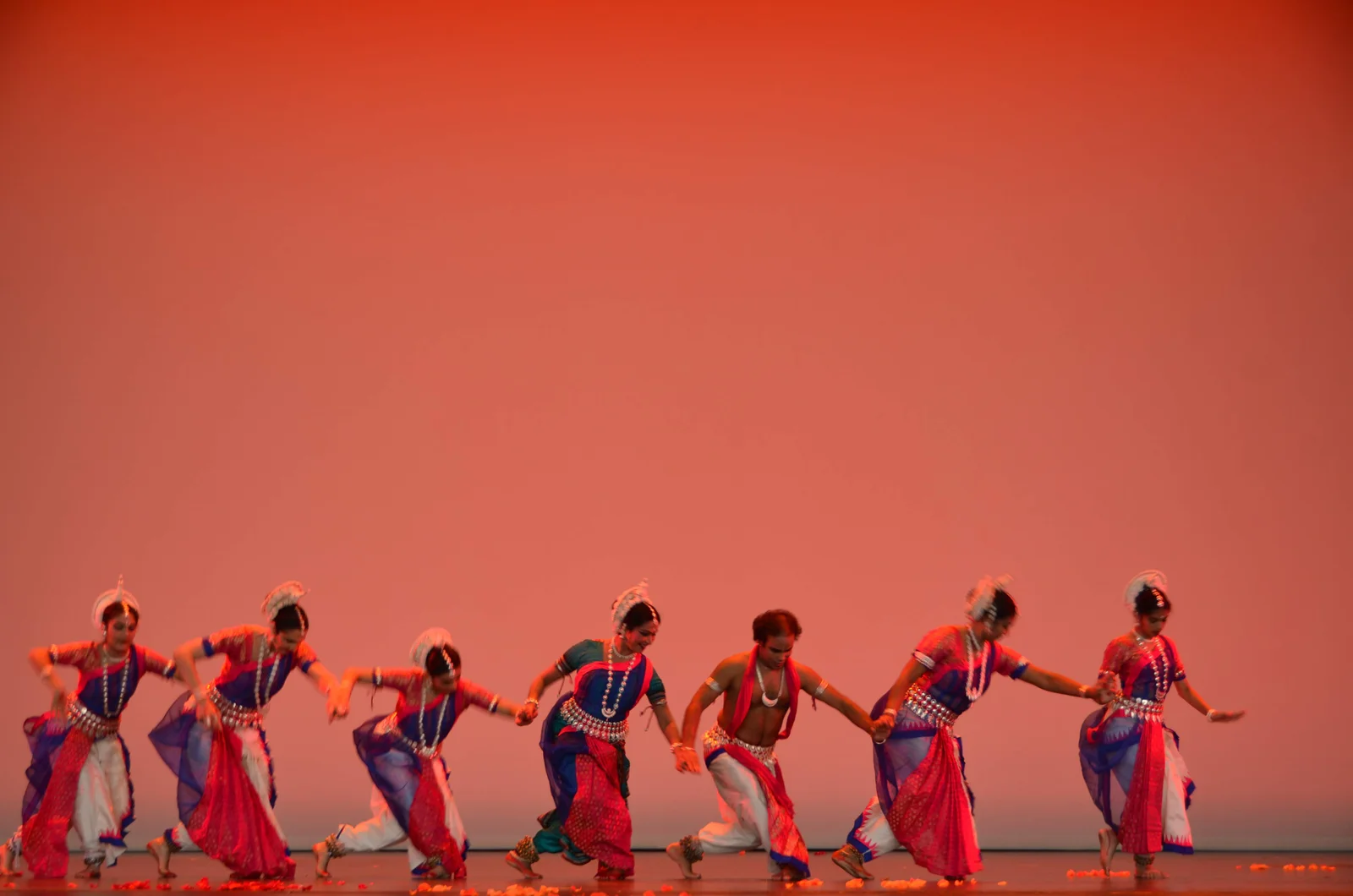 Odissi dancers in traditional attire, gracefully poised with expressive hand gestures and intricate jewelry