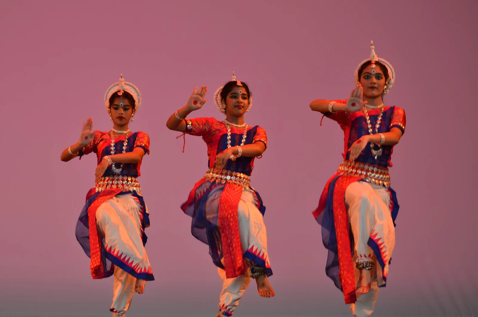 Odissi dancers performing on an outdoor stage at night, illuminated by soft lights