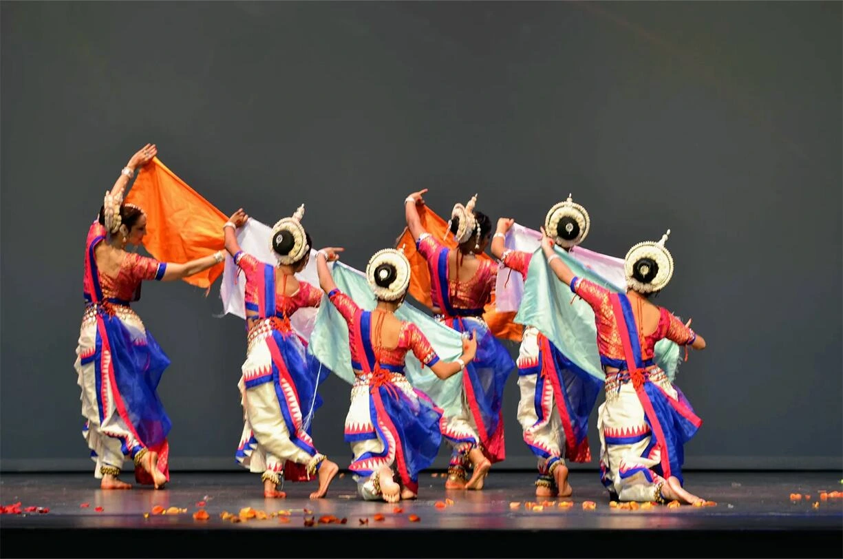 Group of Odissi dancers performing on stage in a graceful formation